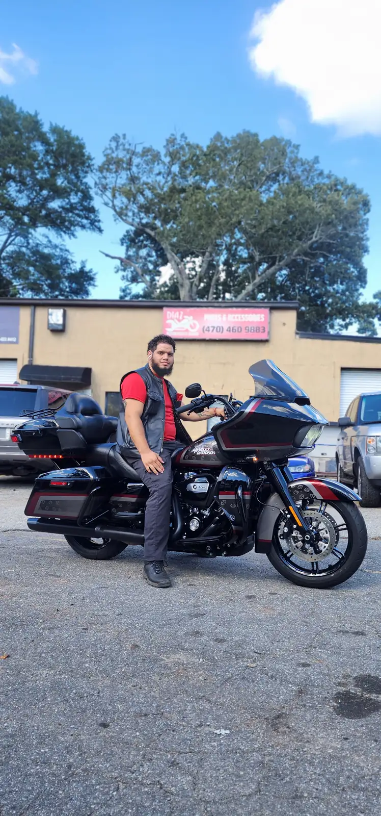 Indie motorcycle service near Mableton — rider in a leather vest leans on a Road Glide Limited in the Diaz shop lot.
