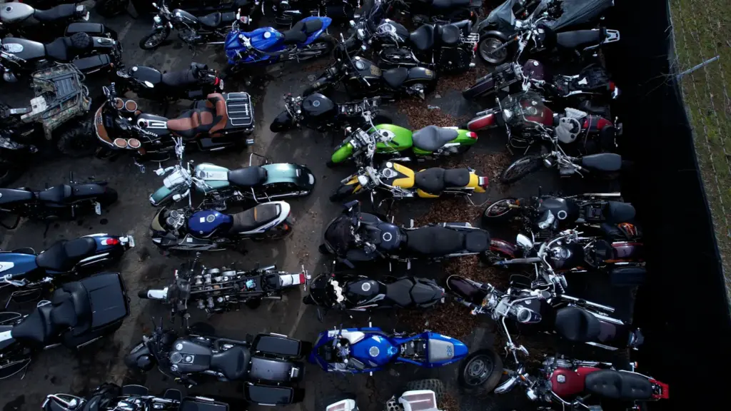 Aerial view of a motorcycle parking lot filled with parked motorcycles of various colors outdoors.