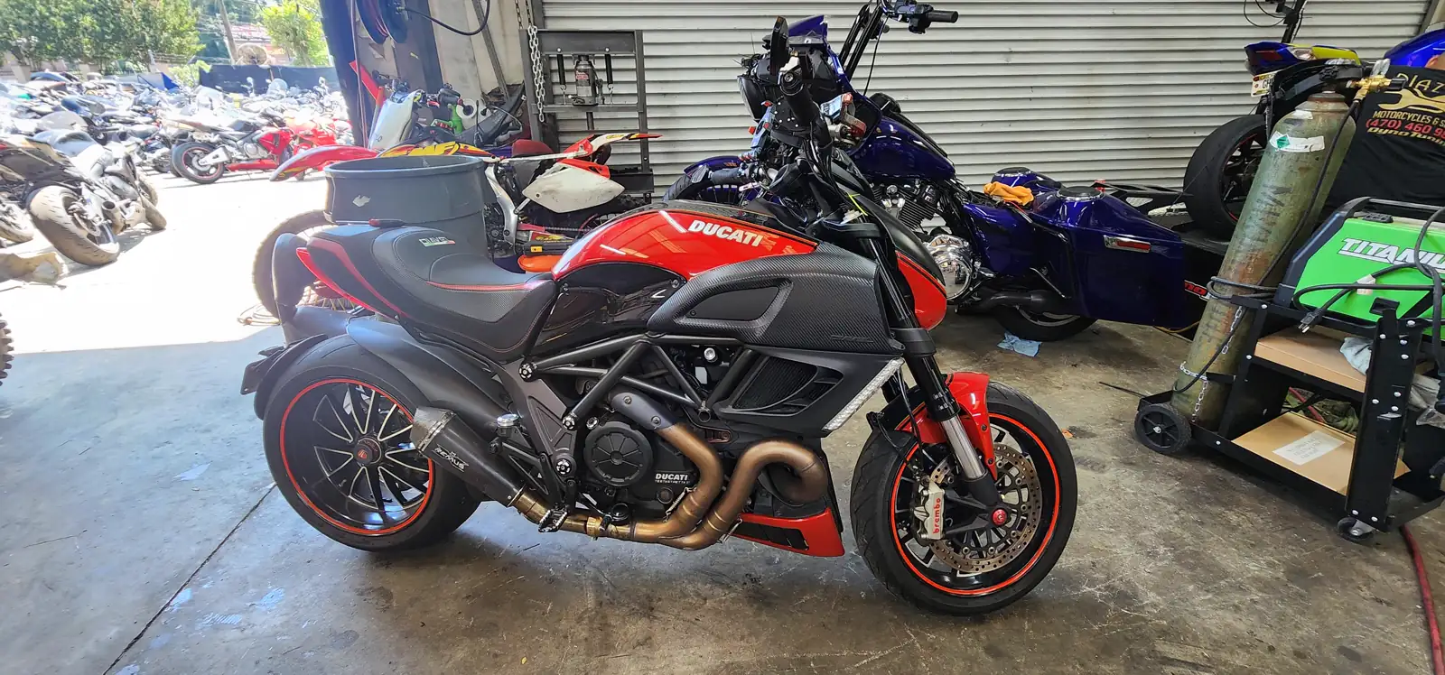 Motorcycle service Lawrenceville riders travel for — red and black Ducati Diavel with carbon parked by a blue Harley bagger.