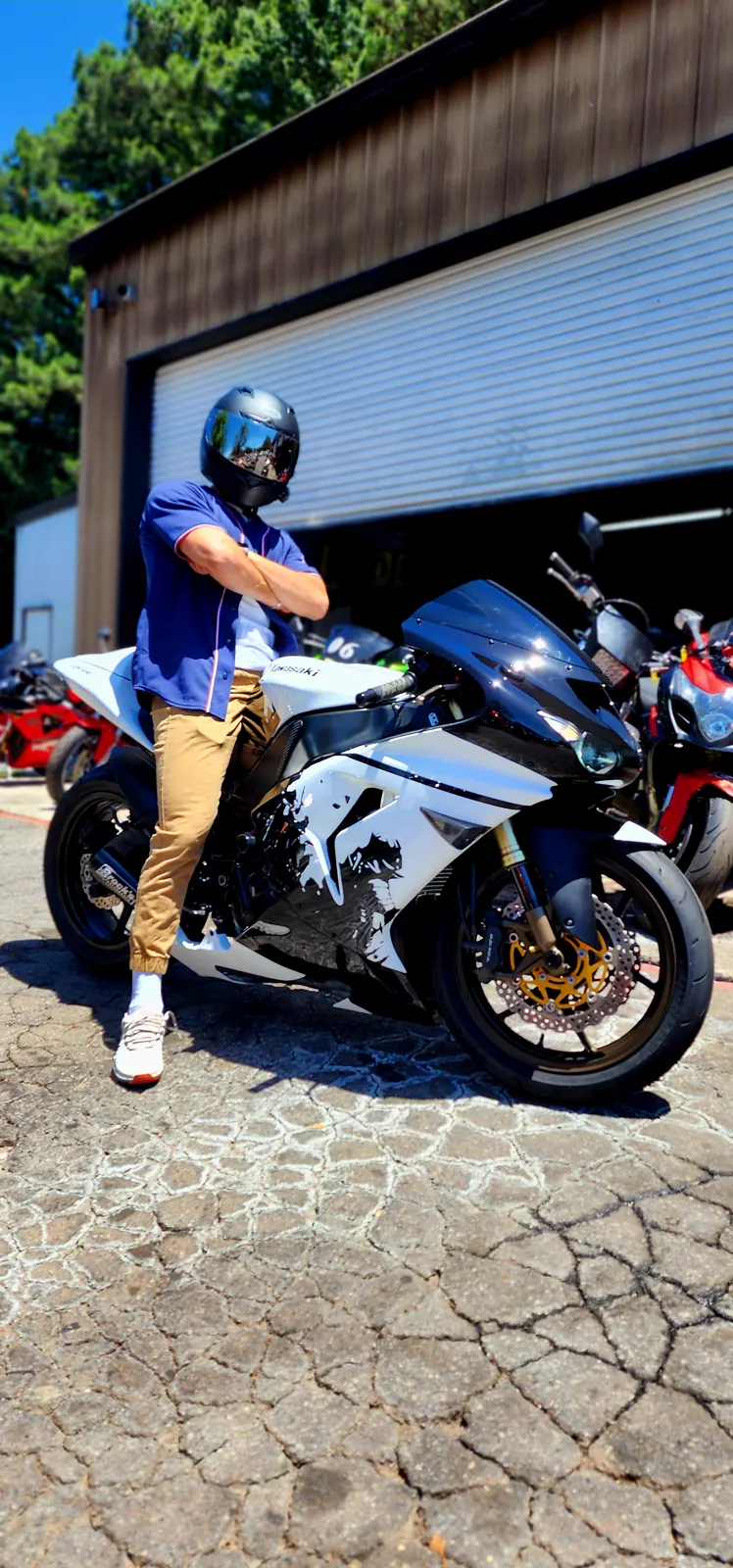 Indie motorcycle service Lawrenceville — rider standing arms crossed beside a white and black Kawasaki sportbike with gold rotors