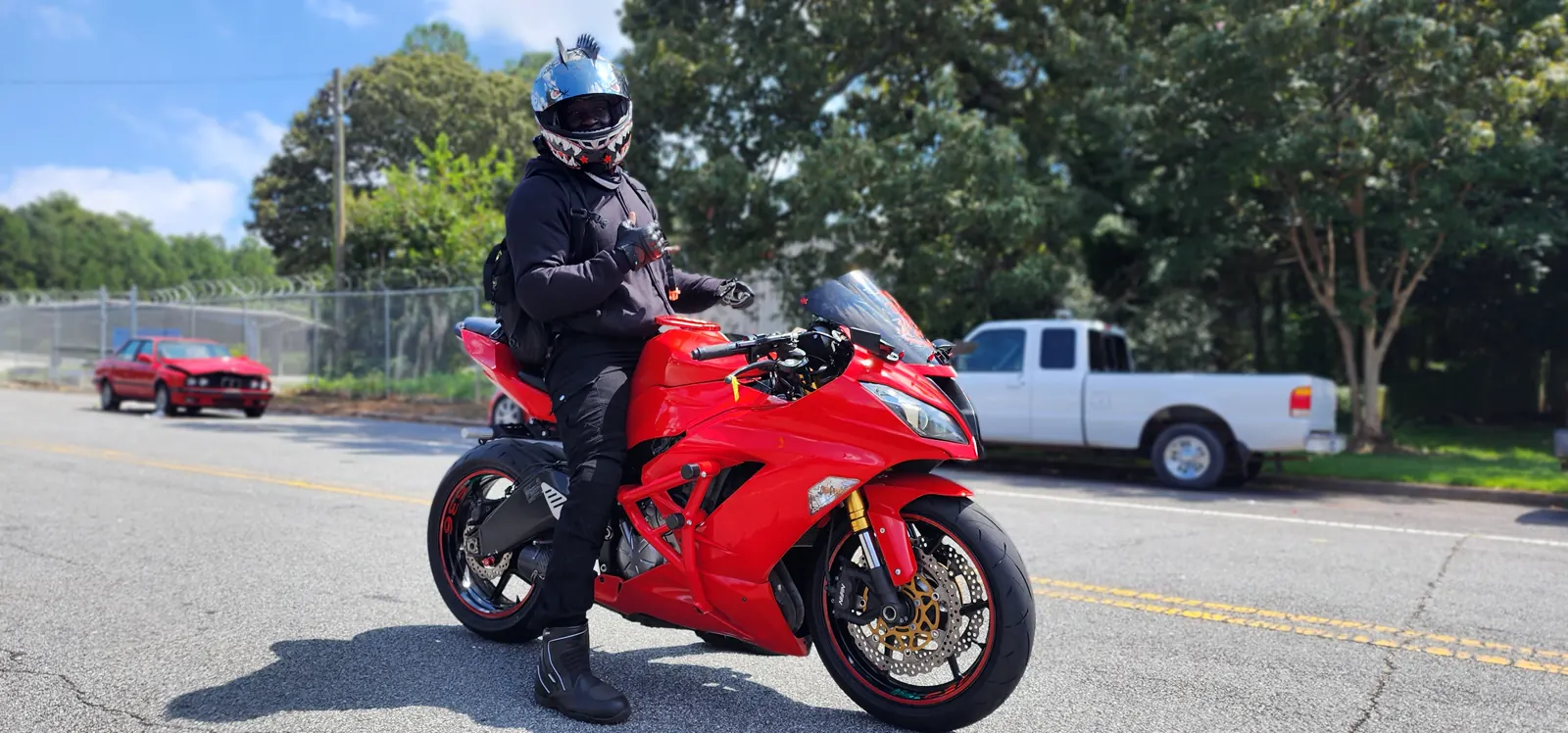 Newnan motorcycle service — rider in full black gear on a bright red sportbike stopped on a sunny street