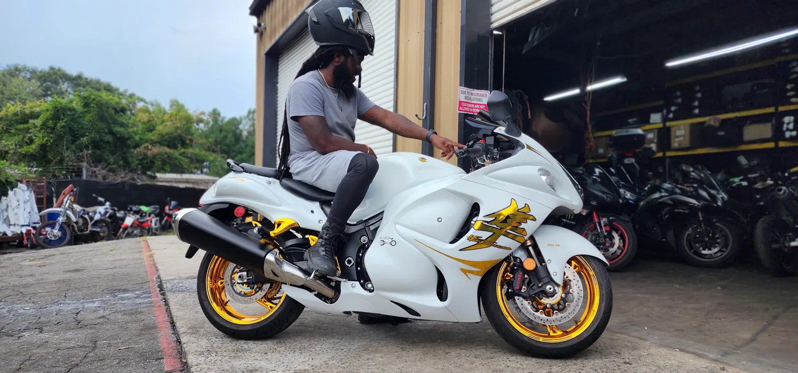 Motorcycle service Newnan riders trust — rider in a helmet on a white Hayabusa outside the open shop bay