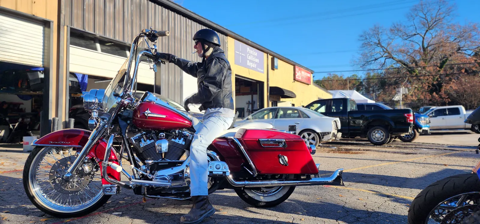 motorcycle maintenance Roswell — rider in leather jacket and helmet on a red Harley-Davidson Road King outside the shop bays