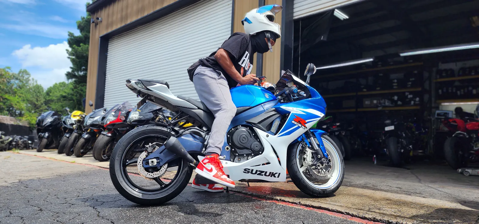 Motorcycle service Roswell — rider in a white helmet on a blue Suzuki GSX-R outside the shop bay