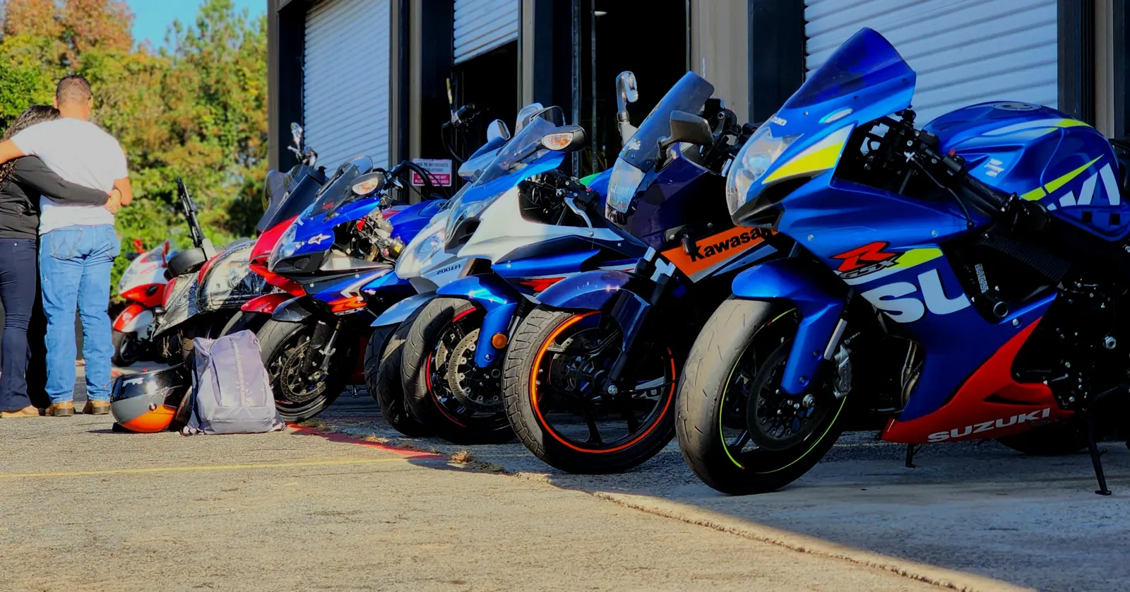 Open transport Mableton — sportbikes parked nose-out at golden hour in front of the shop bays.