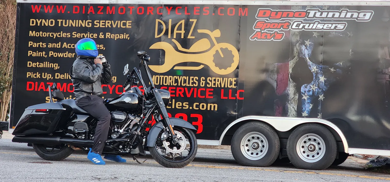 Motorcycle transport Mableton — rider in a helmet by a black Harley Road King and the Diaz service trailer