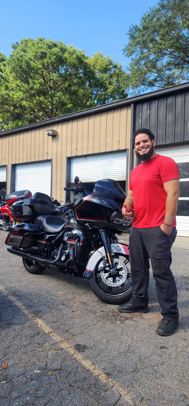 Motorcycle transport Mableton — bearded man in red by a black and red Harley Road Glide Limited at the shop