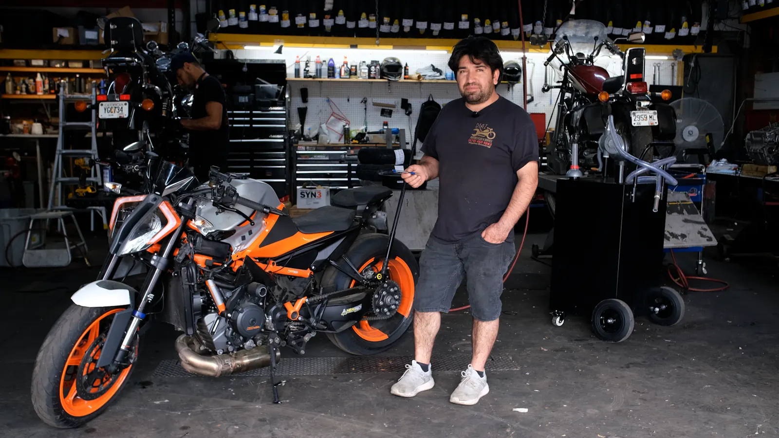Woodstock motorcycle transport — Diaz tech beside an orange and grey KTM naked bike in the shop