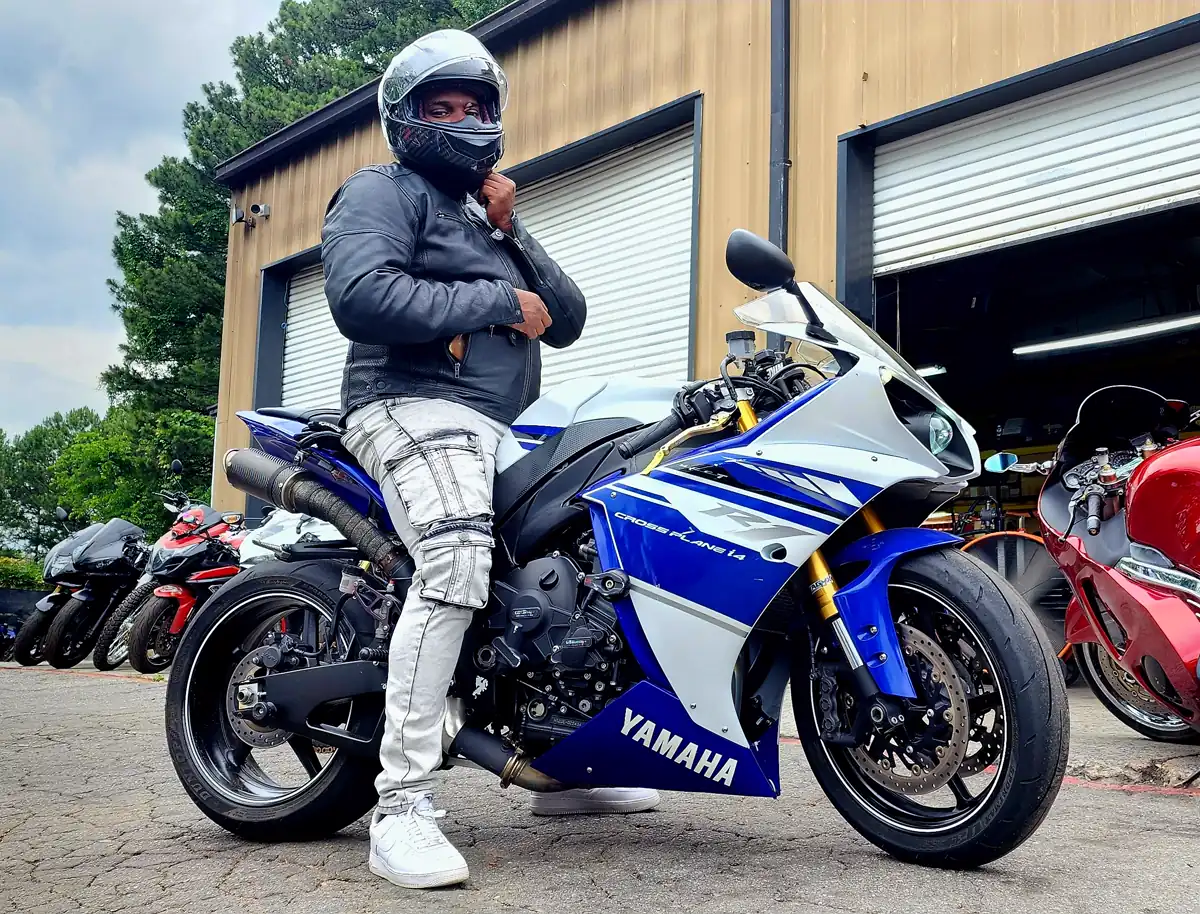 Woodstock motorcycle transport — rider beside a blue and white Yamaha R1 outside the Diaz bay