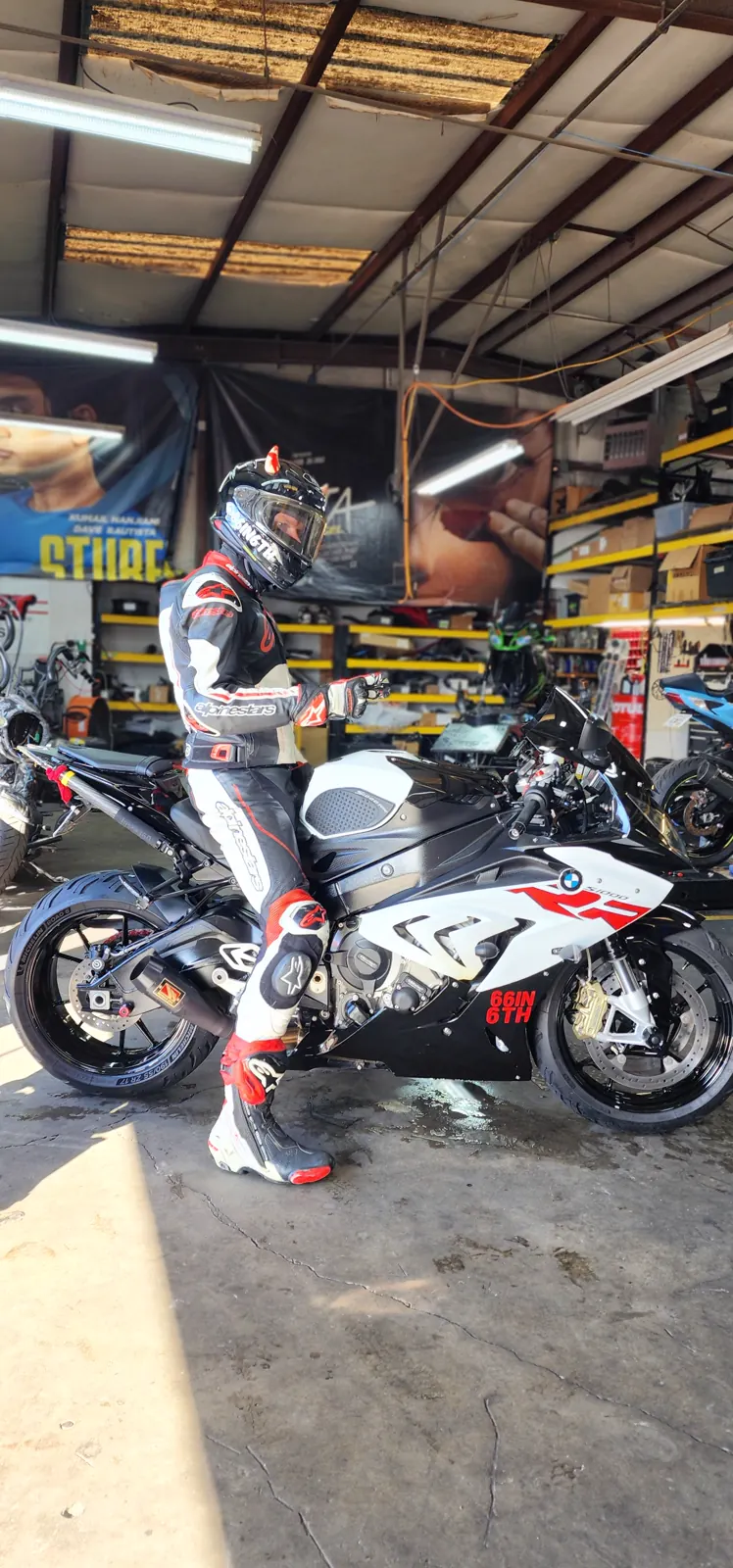 best motorcycle transport Woodstock — rider in red and black leathers on a BMW S1000RR inside the Diaz shop