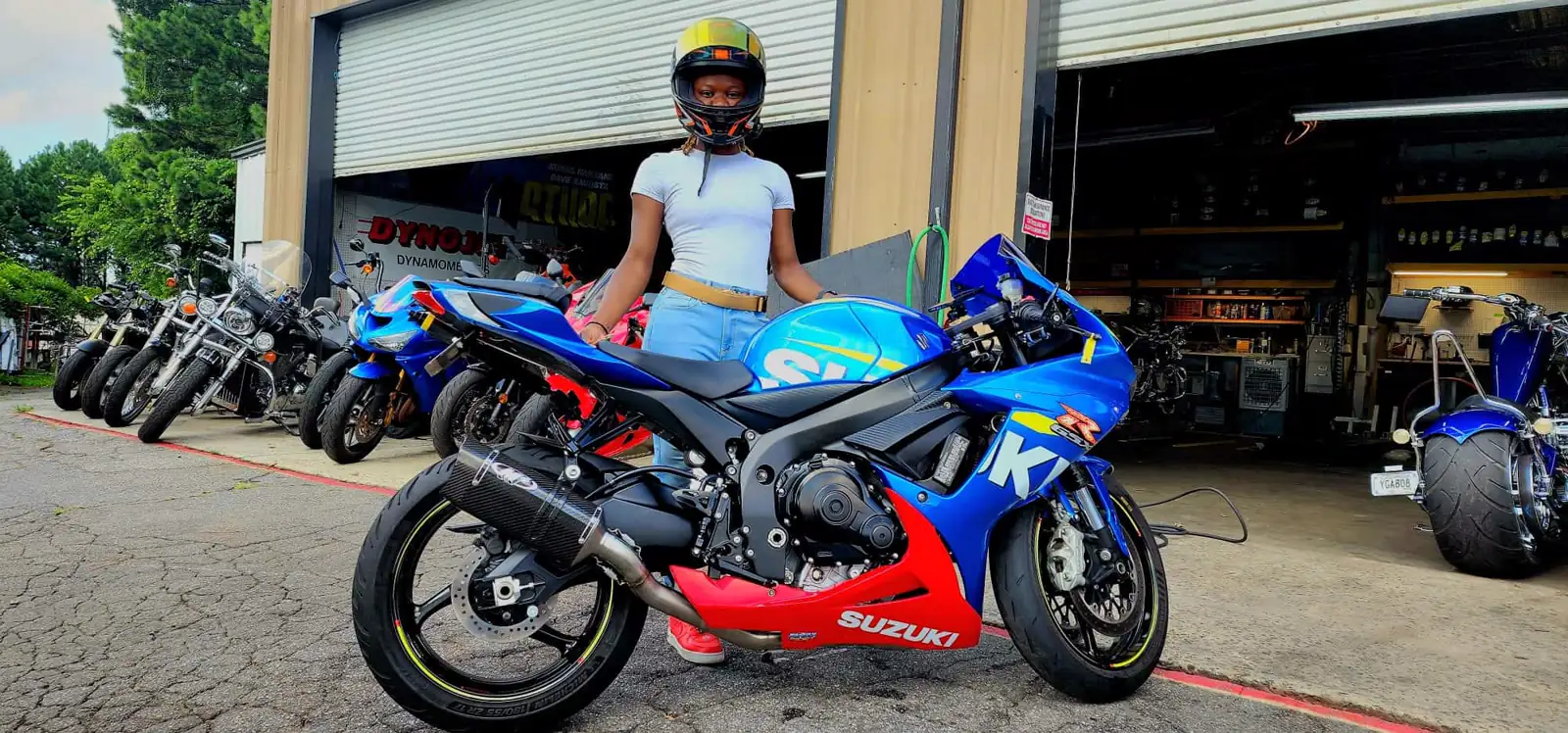 Canton motorcycle transport — rider in a helmet beside a blue and red Suzuki GSX-R in the Diaz shop lot