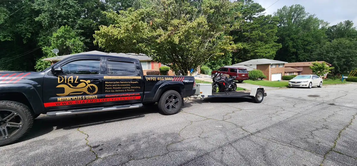 Stranded motorcycle pickup Mableton — Diaz branded pickup and open trailer with a red sportbike strapped on