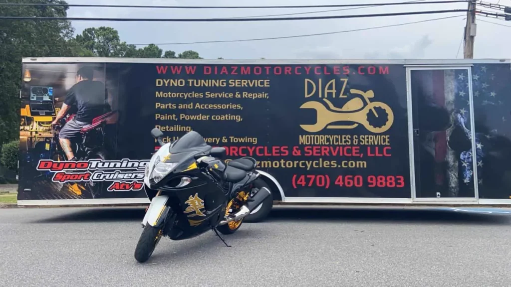 Black and gold Suzuki Hayabusa parked in front of the branded Diaz enclosed trailer on asphalt