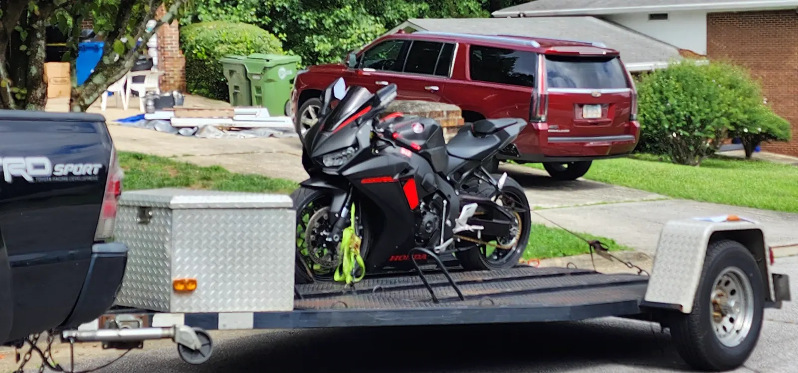 Motorcycle transport Mableton — black Honda CBR strapped with yellow tie-downs on an open trailer