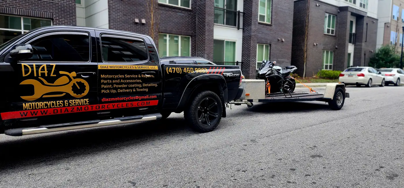 Open transport Mableton — Diaz Tacoma with an open trailer carrying a black sportbike curbside at an apartment.