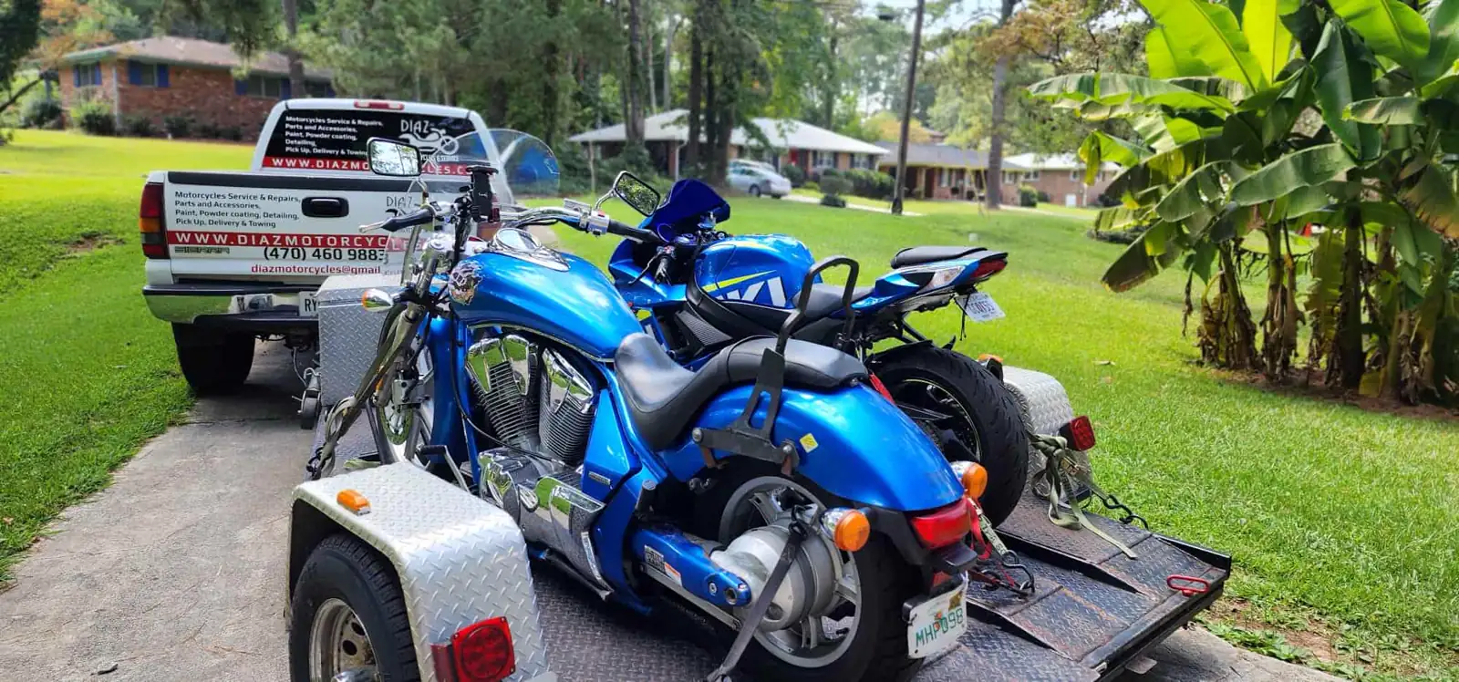 Motorcycle transport Mableton — blue Honda cruiser and blue Suzuki sportbike on a Diaz open trailer