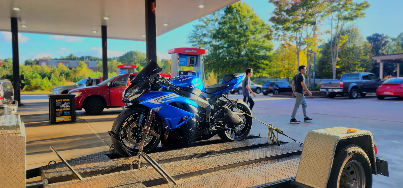 Motorcycle transport Mableton — blue Kawasaki Ninja ZX-6R strapped on an open Diaz trailer under a canopy