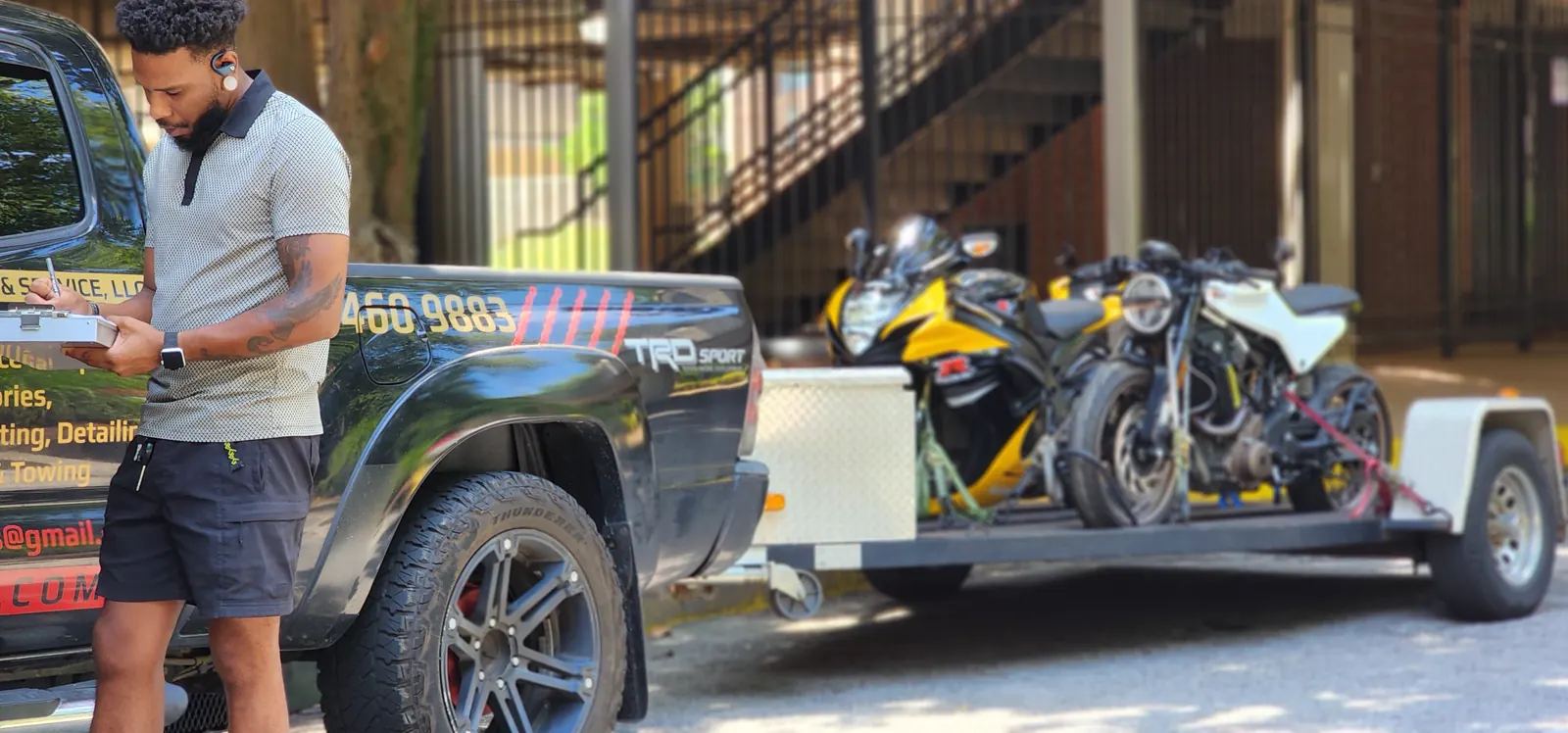 motorcycle shipping East Cobb — Diaz employee with a clipboard writing next to the branded truck and loaded trailer