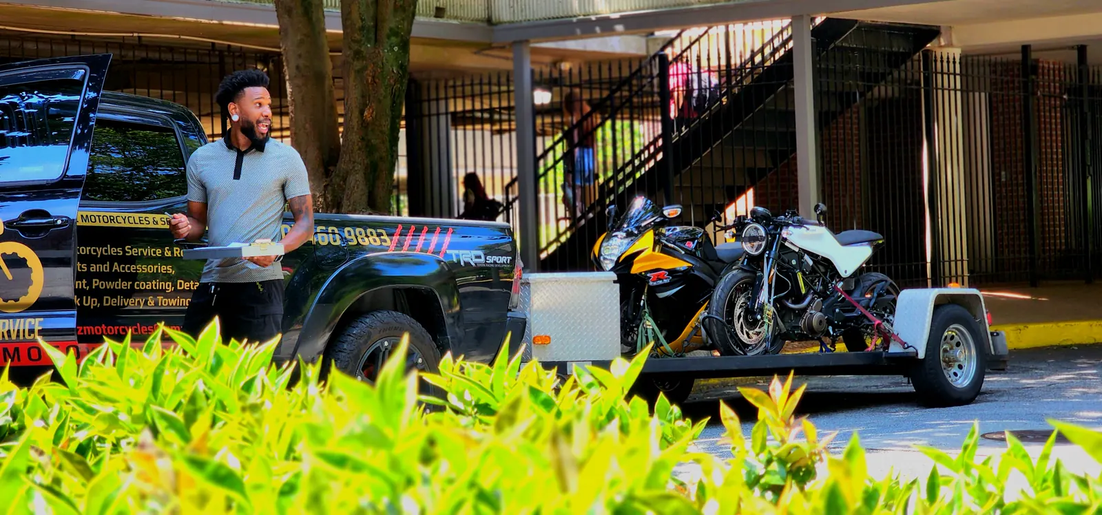 motorcycle transport Acworth — Diaz worker with a clipboard beside the loaded trailer at a pickup