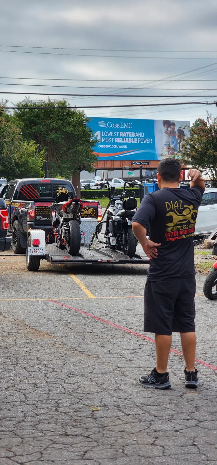 Motorcycle transport Woodstock — Diaz staffer directs a trailer loaded with a stunt bike and a Harley bagger