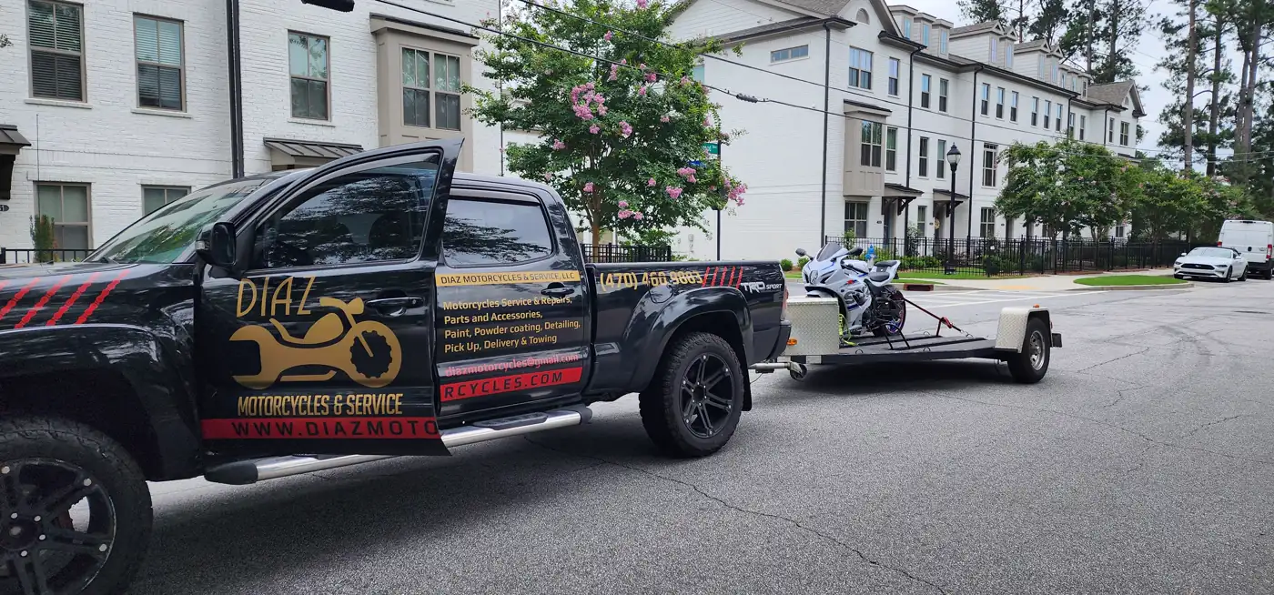 transport company East Cobb — Diaz-wrapped black Tacoma towing an open single-rail trailer with a white sportbike