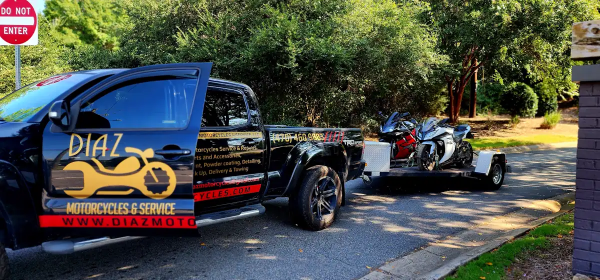 motorcycle transport Woodstock GA — Diaz Tacoma towing red and silver sportbikes on a shaded drive