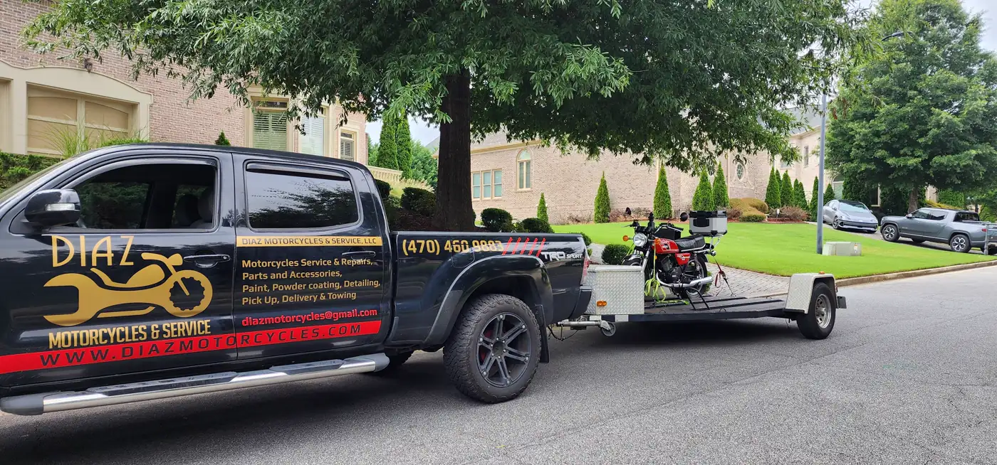 Motorcycle transport Kennesaw — Diaz Tacoma and open trailer carrying a red vintage standard in a brick-home driveway.