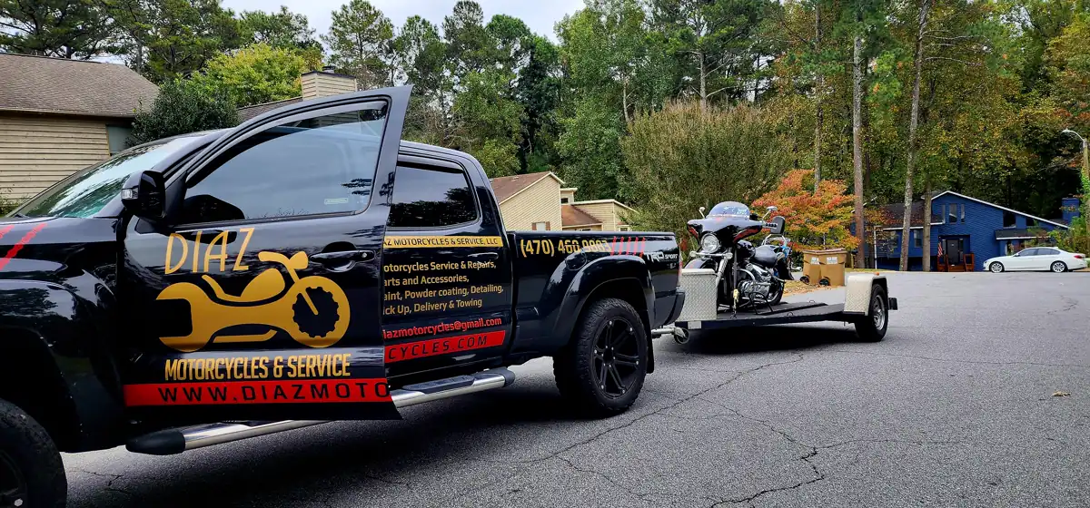 motorcycle transport Kennesaw — Diaz Tacoma tows an open trailer with a Harley bagger on a fall street
