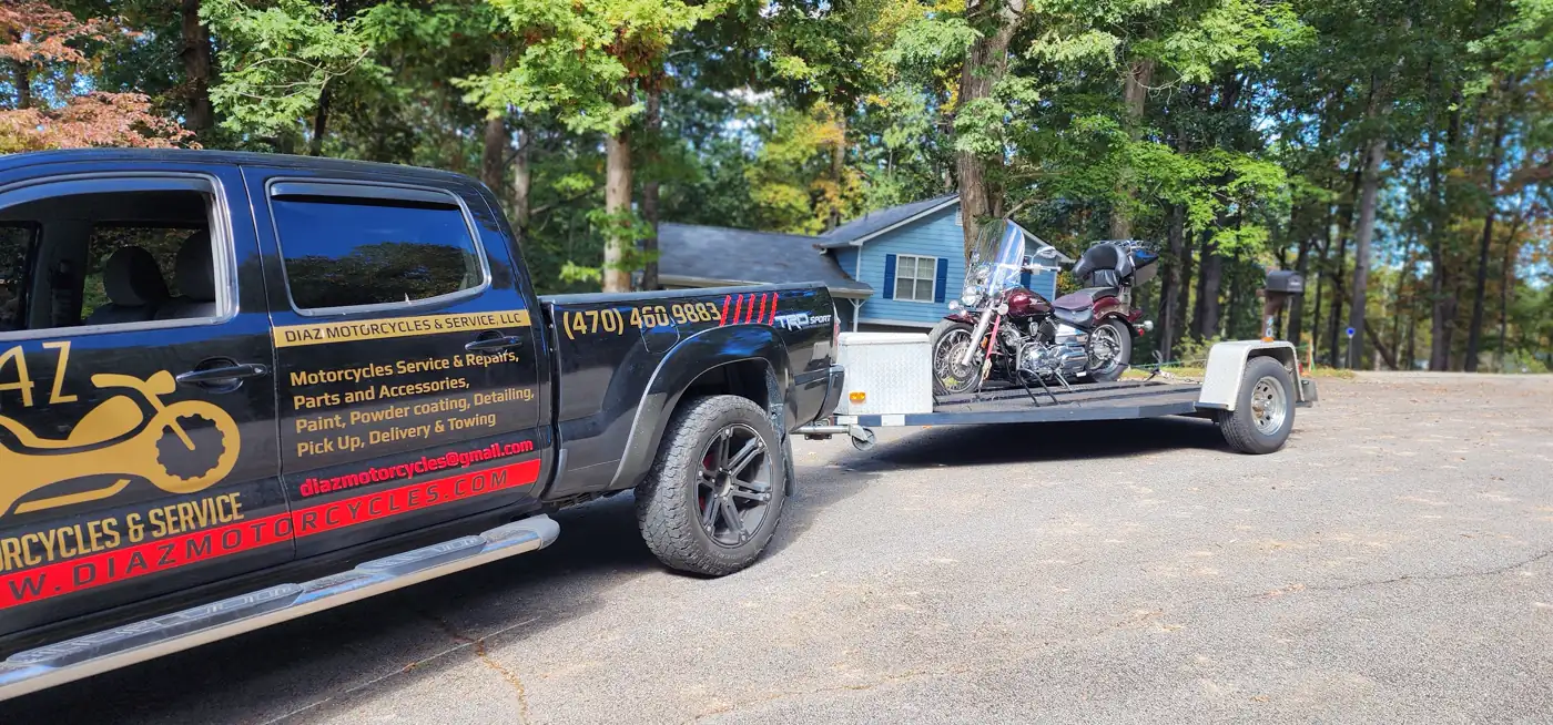 motorcycle transport Canton — Diaz-wrapped Tacoma towing a maroon Harley Softail in a wooded driveway