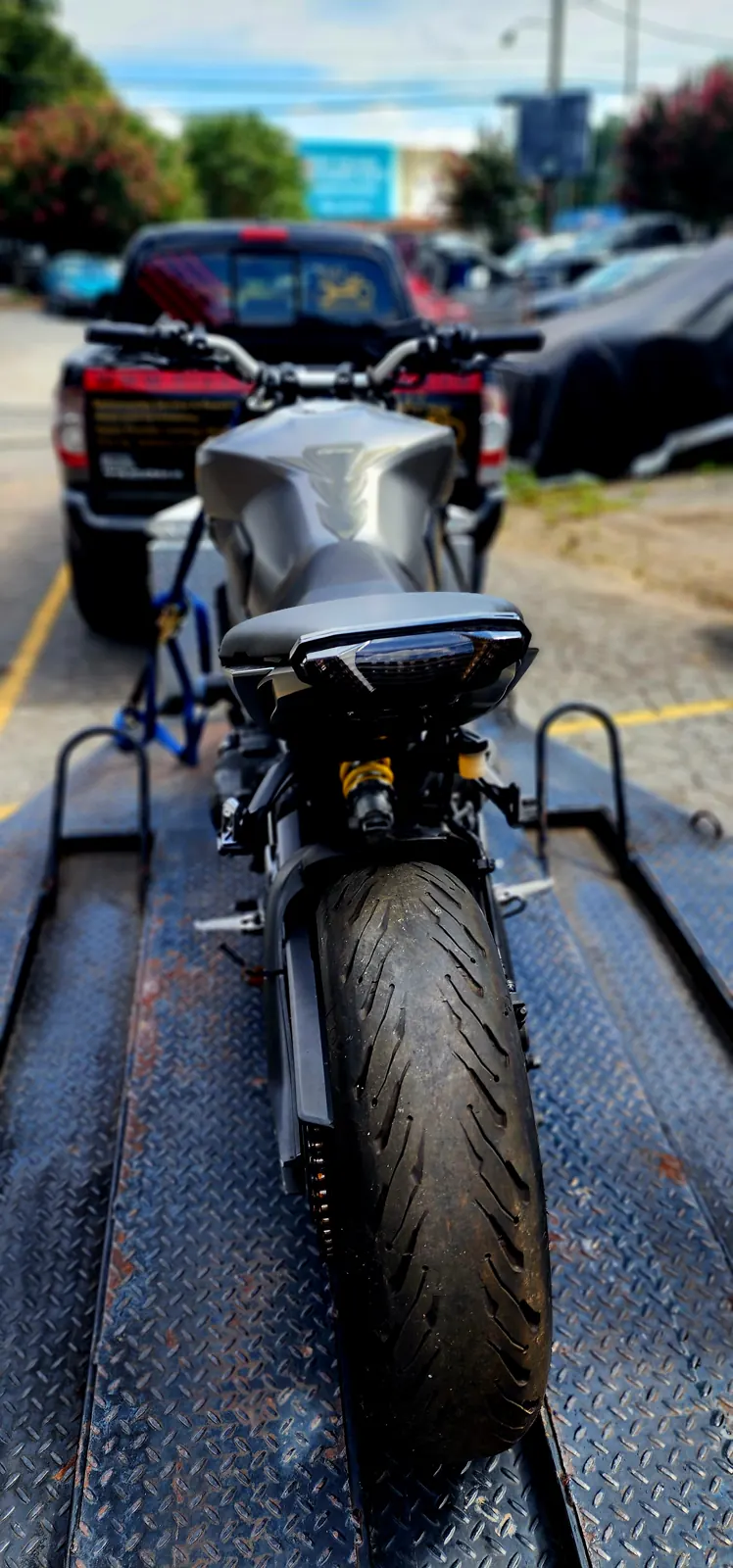 enclosed vs open transport Canton — silver naked bike strapped on the trailer bed with a wheel chock