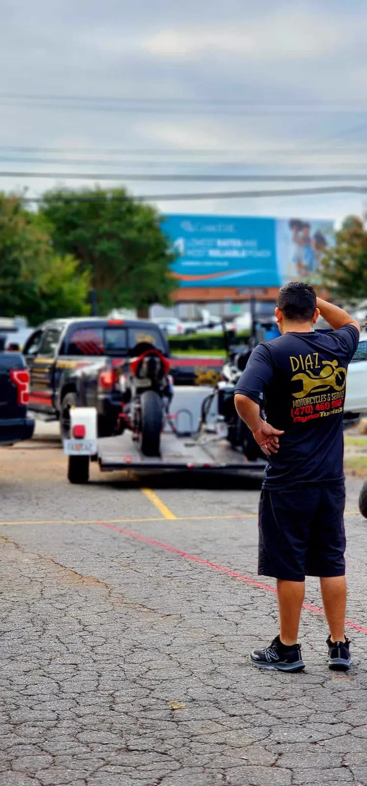 Motorcycle transport Canton — Diaz crew watching a black pickup tow a sportbike on an open trailer