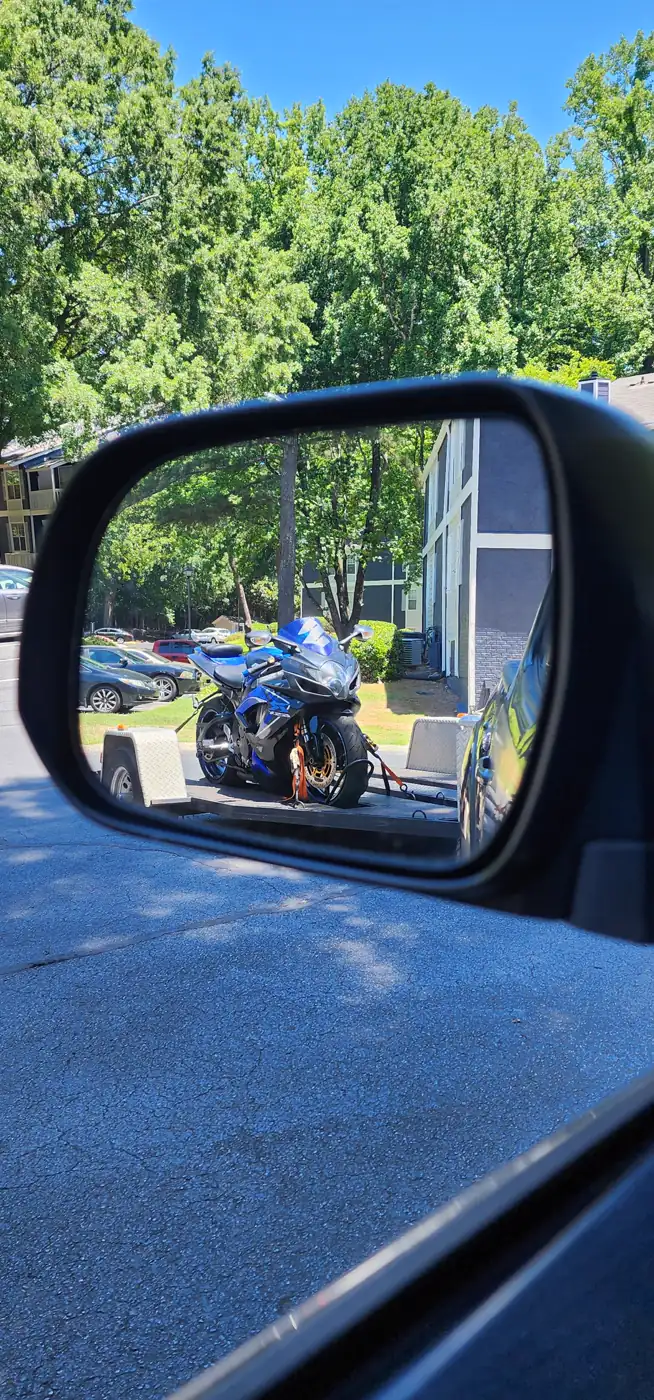 motorcycle pickup Powder Springs — mirror view of a blue Suzuki GSX-R strapped down on an open Diaz trailer
