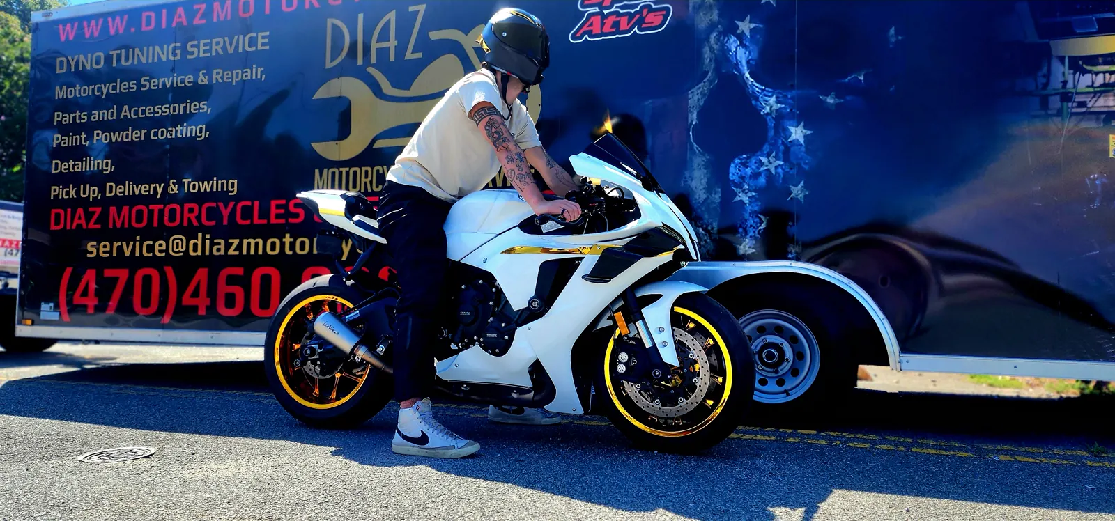 motorcycle transport cost Roswell — rider mounting a white and gold sportbike beside the Diaz trailer