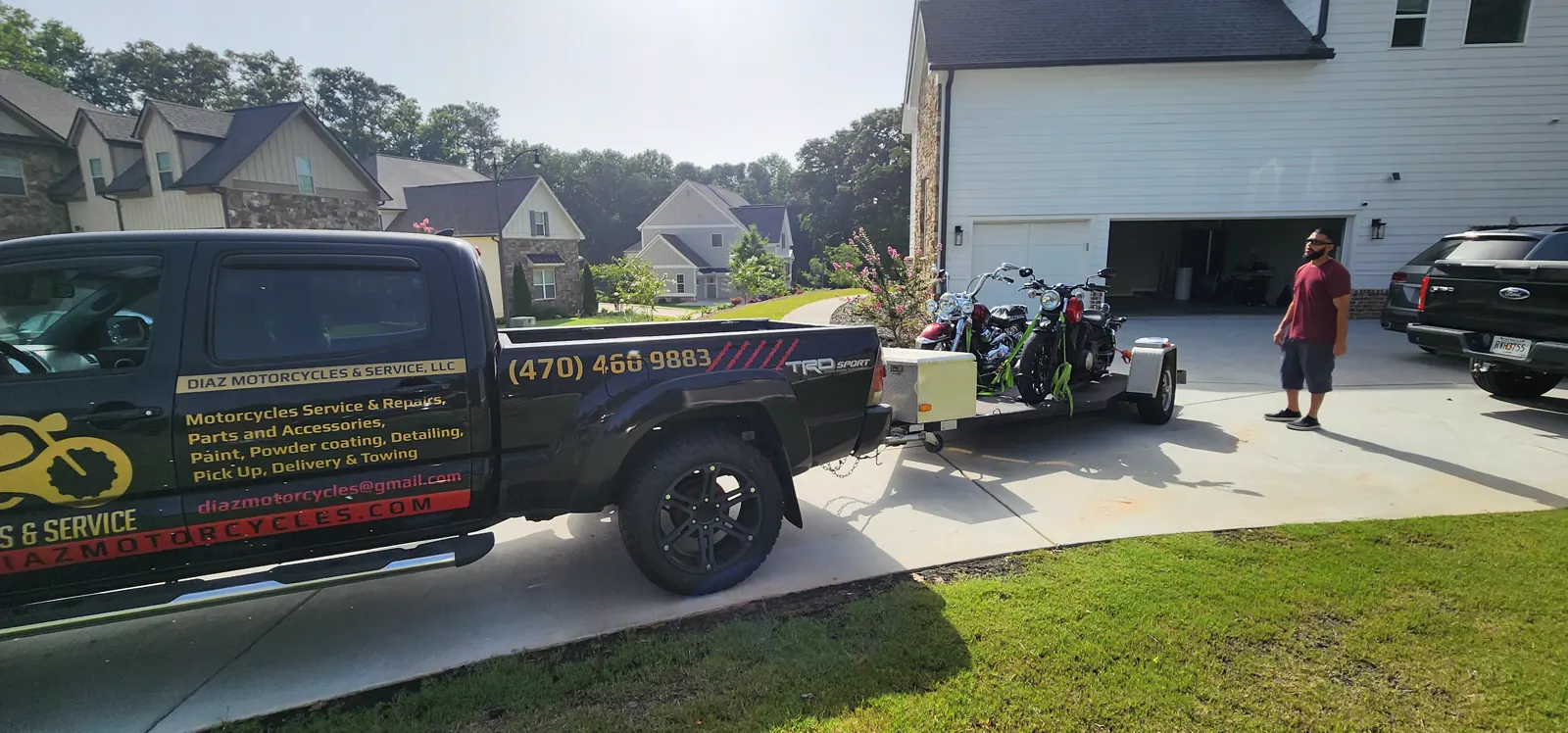 Powder Springs motorcycle pickup — Diaz Tacoma and loaded trailer in a suburban driveway with a customer nearby