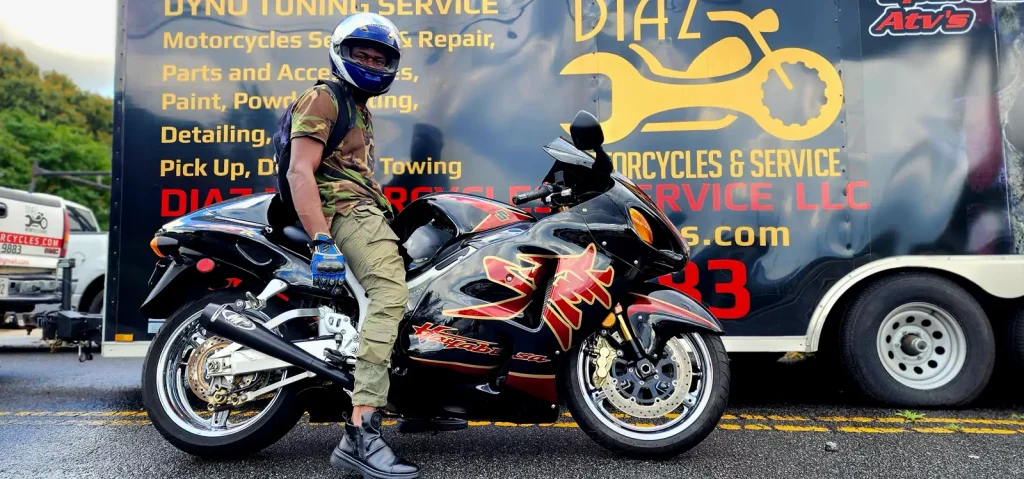 Tight side shot of a rider in camo on a black and red Hayabusa with the Diaz trailer graphics filling the background.