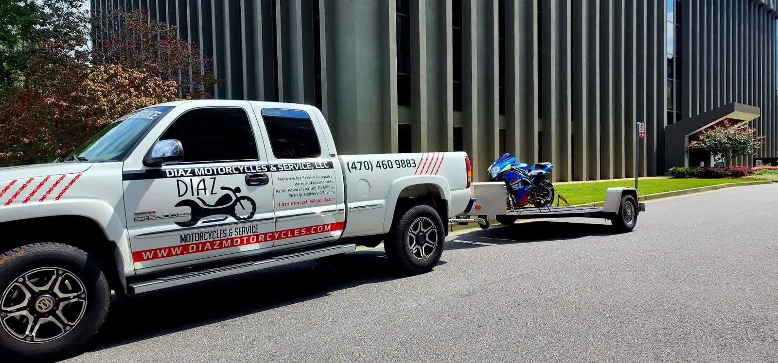 Best motorcycle transport Smyrna — white branded Diaz GMC towing an open trailer with a blue sportbike