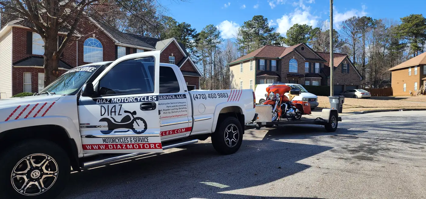 enclosed transport Powder Springs — wrapped Diaz GMC pickup towing an open trailer with an orange Harley bagger